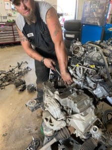 Belly Brothers auto tech working on an engine