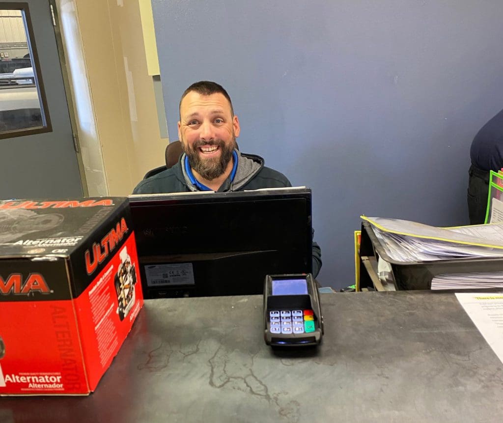 Belly Brothers Auto Tech smiling while working on computer