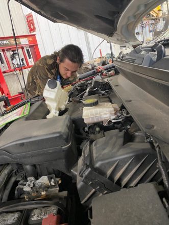 Belly Brother auto tech working on a engine