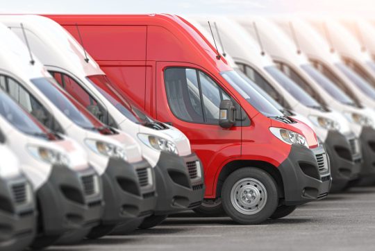 Red delivery van in a row of white vans. Red delivery van in a row of white vans.